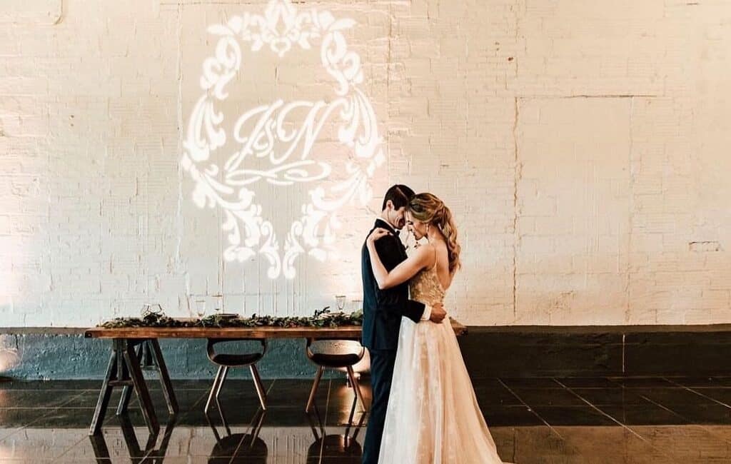 wedding couple snuggled up close next to their custom monogram created by icon events group for their wedding